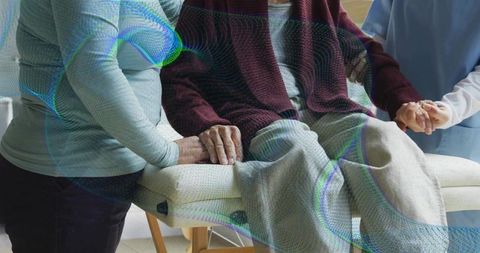 Elderly woman sitting on clinic bench with caregiver supporting arm and nurse holding hand