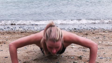 Woman Exercising with Push-Ups on Beach Near Ocean