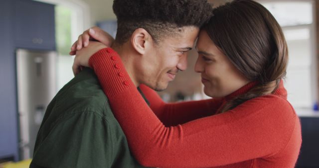 Happy biracial couple embracing and smiling together in kitchen - Download Free Stock Photos Pikwizard.com