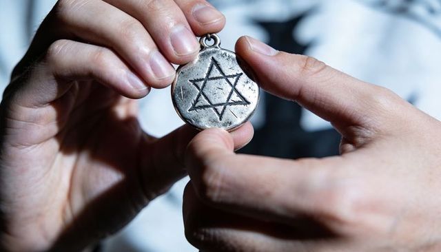 Holding worn hexagram medallion engraved star of david, studying patina and detail