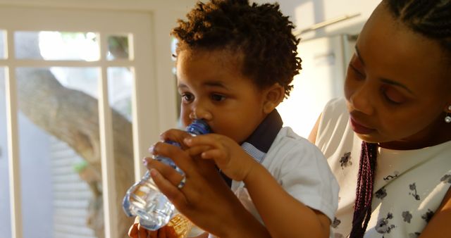 Caring Mother Helping Toddler Drink Water from Bottle in Sunlit Room - Download Free Stock Images Pikwizard.com