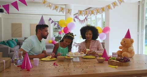 Family celebrating birthday at home with cupcakes and festive decor