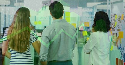 Colleagues planning strategy with transparent glass whiteboard