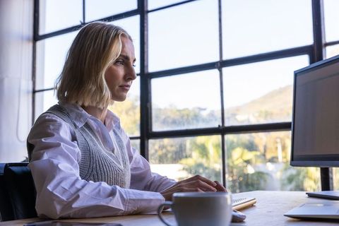 Professional woman working at modern office desk with monitor