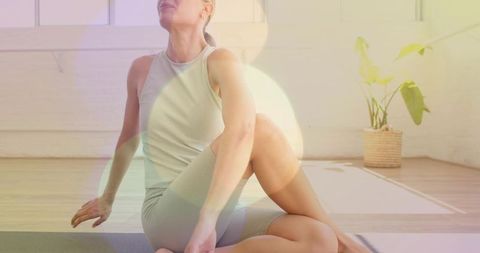 Woman Performing Seated Spinal Twist on Yoga Mat in Bright Minimal Home Studio