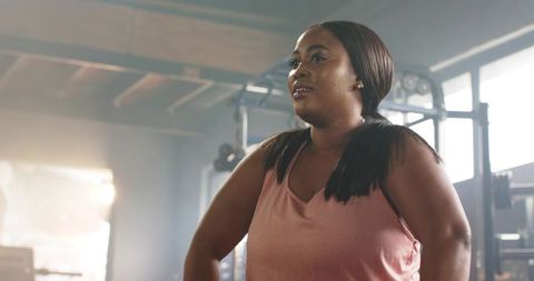 Determined african american woman strength training in sunlit gym wearing pink tank top