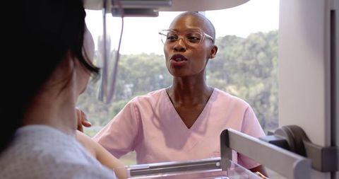Black Female Mammography Technologist Guiding Patient Through Mammogram Breast Screening