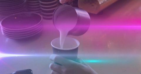 Caucasian man pouring milk into coffee with colorful light effects