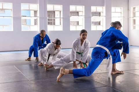 Martial artists practicing stretches in a sunlit dojo