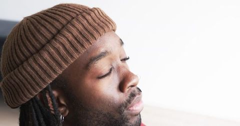African American male wearing brown ribbed beanie and hoop earring in soft light closeup