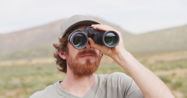 Bearded caucasian male survivalist using binoculars in wilderness. exploration, travel and adventure, survivalist in nature.