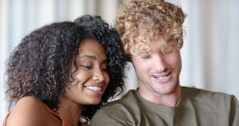 Interracial couple leaning and smiling on couch, relaxing intimate candid portrait