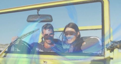 Couple driving yellow convertible on sunlit road windblown hair enjoying adventure