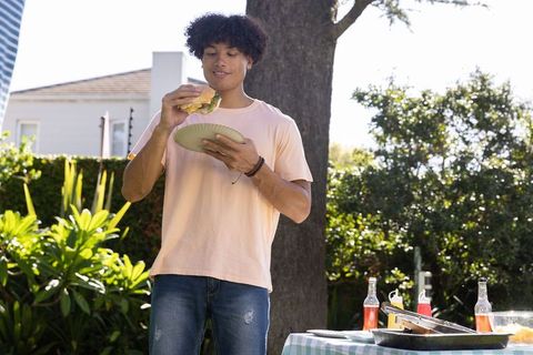 Man Enjoying Hamburger at Backyard Summer Gather Cooking