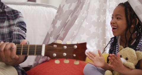 Father and Daughter Enjoying Music in Cozy Indoor Tent