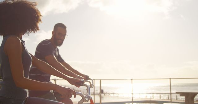 Romantic diverse couple riding bikes and smiling on sunny beach, copy space - Download Free Stock Photos Pikwizard.com