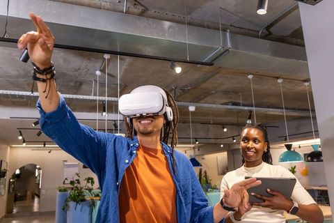 African American coworkers demonstrating virtual reality headset in modern open office