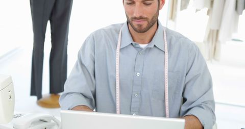 Fashion designer working on laptop in tailoring studio