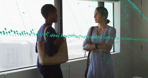 Two businesswomen talking by office window with tote bag and city skyline overlay