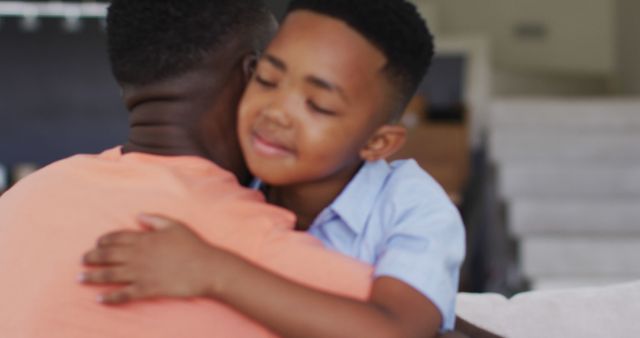 Shows close-up of father hugging young son with tenderness at home. Great for family bonding themes, father’s day promotions, parenting articles, and promoting family-related products or services.