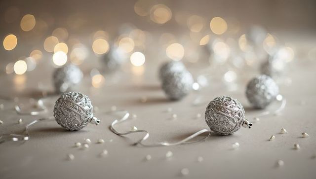 Silver filigree baubles decorating neutral holiday tabletop with warm bokeh lights