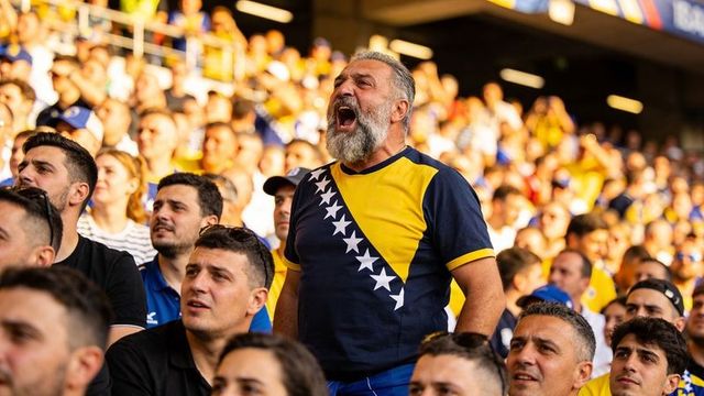 Passionate older fan shouting in bosnia and herzegovina jersey among sunlit stadium crowd