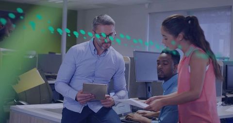 Manager Leading Team Collaborating Around Tablet in Open Office Cubicles with Monitors