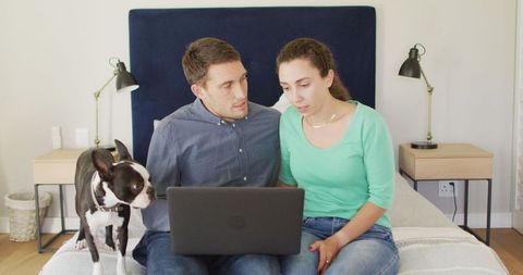 Couple paying bills online with laptop at home