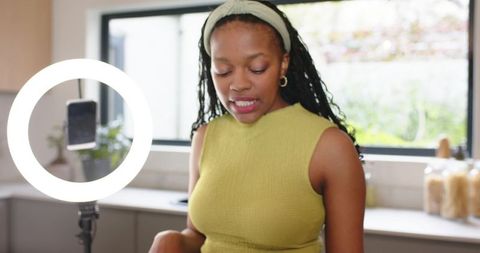 African american woman recording cooking tutorial in modern kitchen with ring light