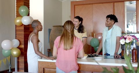 Diverse Group of Friends Socializing in Kitchen at Home Celebration