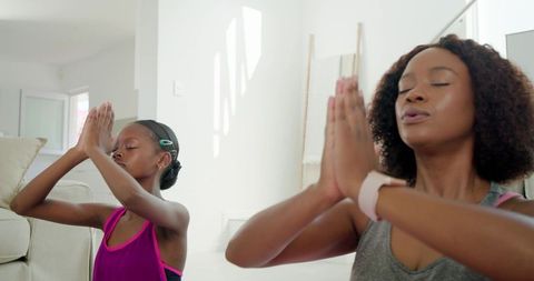 Mother and daughter practicing mindful meditation in sunlit minimal living room