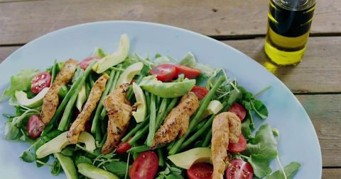 Grilled chicken avocado salad featuring green beans cherry tomatoes and olive oil