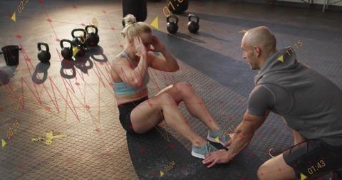 Female Athlete Doing Sit-ups with Coach in Gym Setting