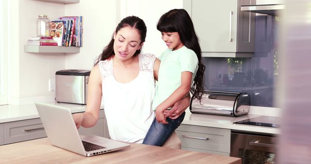 Mother Holding Daughter While Using Laptop in Modern Kitchen - Download Free Stock Images Pikwizard.com