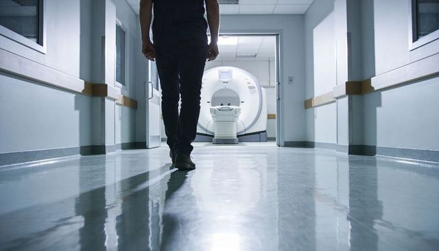 Walking toward ct scanner in sterile hospital corridor with reflective floor and handrails