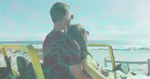 Couple embracing while enjoying coastal buggy ride watching ocean on sunlit beach