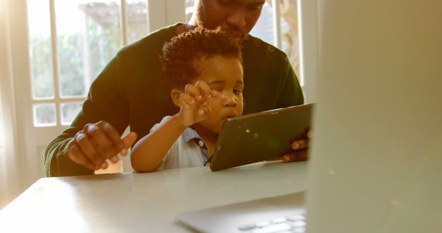 Father and child using digital tablet in sunlit home - Download Free Stock Images Pikwizard.com