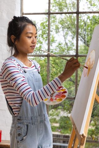 Asian female artist painting on canvas in studio