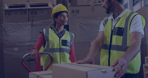 Warehouse workers communicating while moving boxes with pallet jack in distribution center