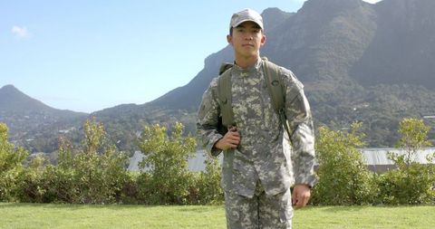 Asian soldier in camouflage uniform outdoors with mountain background