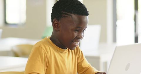 Smiling African American Boy Studying on Laptop in Bright Modern Classroom for Learning