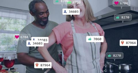 Mature interracial couple cooking together in cozy modern kitchen with social reactions