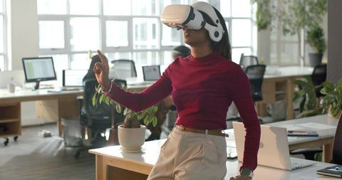 Diverse female team member demonstrating virtual reality headset in modern open-plan office