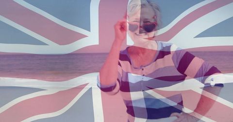 Senior woman celebrating british seaside lifestyle wearing heart sunglasses with union jack overlay