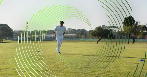 Male cricketer walking across sunlit outfield during training with green graphic rings
