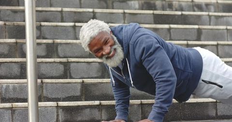 Senior african american man doing pushups on urban steps showing strength and vitality