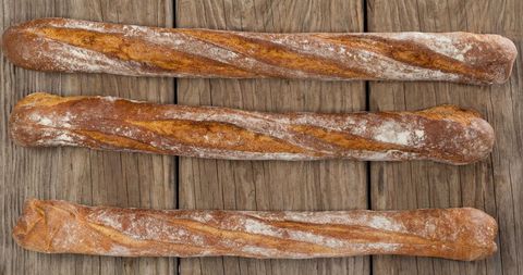 Three fresh baguettes displayed on rustic wooden table