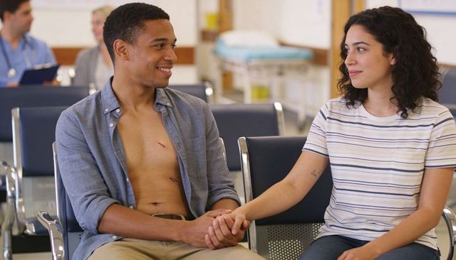 Holding hands in clinic waiting room, man with chest wounds and supportive partner