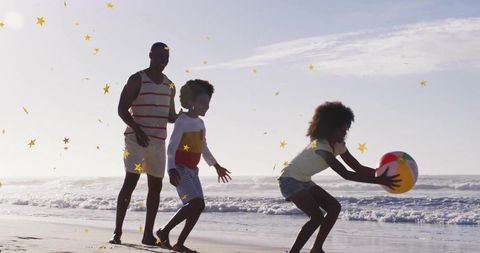 Family playing with beach ball on sunny shoreline