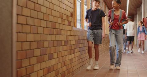 Diverse students walking in school corridor with backpacks